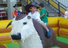 Kleiner Junge hat Spaß auf großem Rodeo Bullen