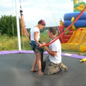 Mann befestigt Mädchen an dem Bungee Trampolin